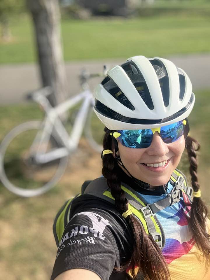 Woman smiling in cycling gear outdoors, representing the journey to reinvent yourself after 50.