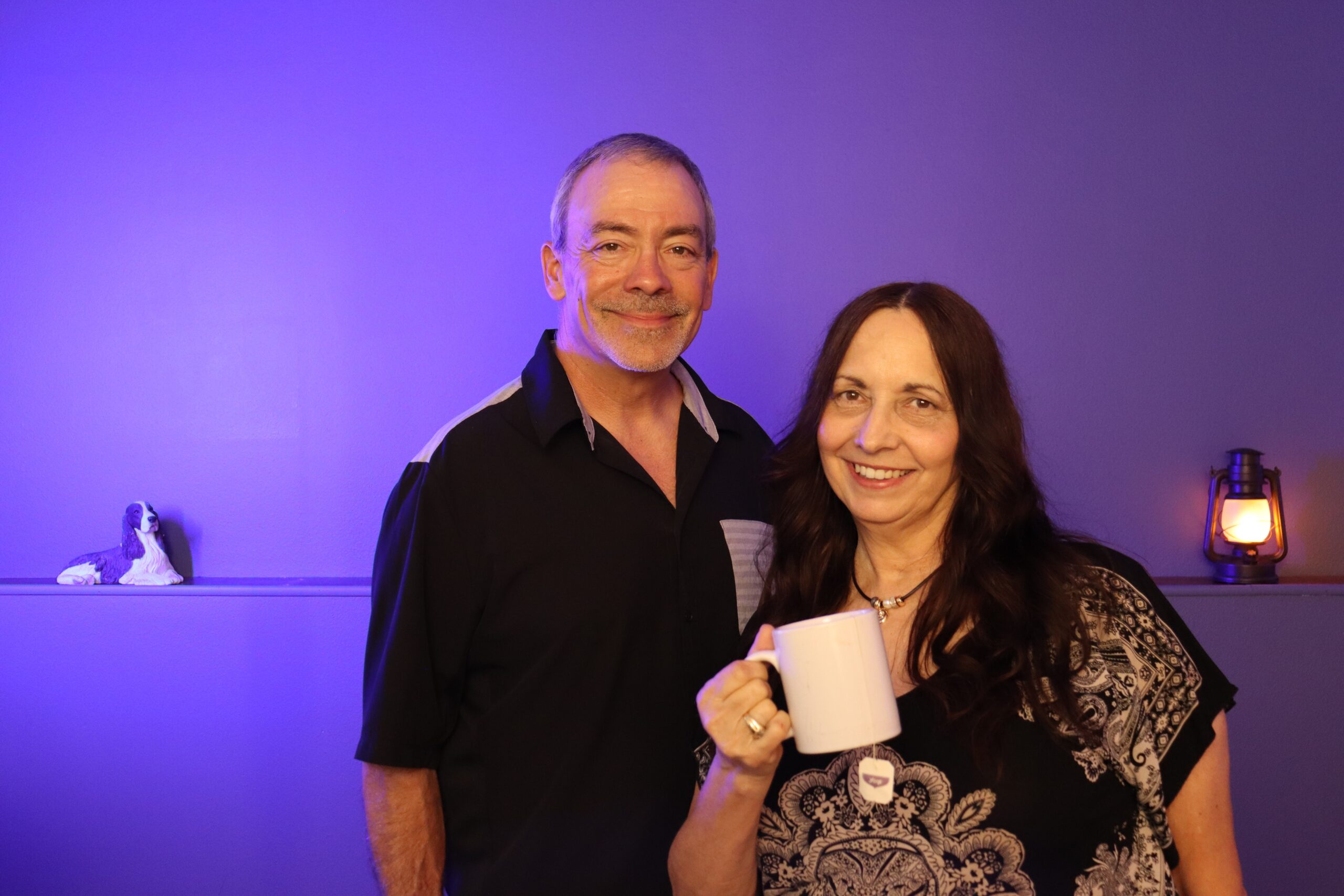 Donna and Terry from Rebuild With Clarity smiling together as Donna holds a warm white mug of tea